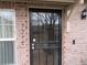 Close-up of front door with secure metal screen and brick facade detailing at 559 Alton Way # C, Denver, CO 80230