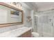A well-lit bathroom with a marble countertop vanity, decorative mirror, and a glass-enclosed shower at 12467 Topaz Vista Way, Castle Pines, CO 80108