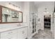 Bright, modern bathroom with dual sinks, marble countertops, large mirror and access to walk-in closet at 12467 Topaz Vista Way, Castle Pines, CO 80108