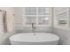 Elegant bathroom featuring a freestanding tub beneath a window with shutters, and white marble tile surround at 12467 Topaz Vista Way, Castle Pines, CO 80108