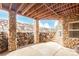 A covered patio with a stone and wood pergola featuring an outdoor dining area and rustic stone pillars at 12467 Topaz Vista Way, Castle Pines, CO 80108