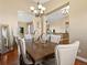 Elegant dining room with hardwood floors, modern chandelier, and views into the kitchen and living area at 14077 Indianfield Ct, Hudson, CO 80642
