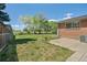 Spacious backyard featuring patio, brick home exterior, trees and chain link fence at 717 E 4Th Ave, Longmont, CO 80504