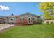 Charming brick home featuring a wooden ramp for accessibility and a well-manicured front yard at 717 E 4Th Ave, Longmont, CO 80504