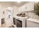 Bright laundry room featuring modern washer and dryer with white overhead cabinets and extra freezer for convenience at 1680 Simms St, Lakewood, CO 80215