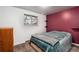 Cozy bedroom with a queen size bed, bright window, carpet flooring, and a burgundy accent wall at 6903 W 52Nd Pl, Arvada, CO 80002