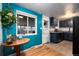 Bright kitchen area with hardwood floors, a window providing natural light, and stylish blue accent wall at 6903 W 52Nd Pl, Arvada, CO 80002