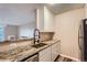 Modern kitchen with granite countertops, stainless steel sink and dark fixtures adjacent to the living room at 2231 S Vaughn Way # 114B, Aurora, CO 80014