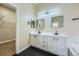 Modern bathroom featuring dual sinks, white cabinets, black hardware, and a walk-in closet at 6596 Silverleaf Ave, Firestone, CO 80504