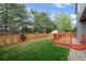 Green backyard with lawn, wooden fence, trees and a wooden deck space for outdoor entertainment at 9522 Castle Ridge Cir, Highlands Ranch, CO 80129