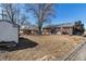 A spacious backyard featuring a brick house, storage shed, and mature trees on a sunny day at 7232 Kalamath St, Denver, CO 80221