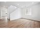 Bright living room features wood-look floors, a large window, and adjacent staircase, offering an inviting atmosphere at 24737 E 40Th Ave, Aurora, CO 80019