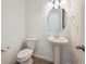 Simple powder room features a pedestal sink, oval mirror, and wood-look floors at 24737 E 40Th Ave, Aurora, CO 80019