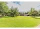 Expansive backyard featuring lush green lawn, mature trees, and a wooden fence in the background at 13990 Berry Rd, Golden, CO 80401