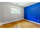 Bedroom with hardwood floors, window, and bright blue accent wall at 13990 Berry Rd, Golden, CO 80401