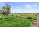 Serene backyard view featuring a wooden fence, lush greenery, and open field at 5864 Turnstone Pl, Castle Rock, CO 80104