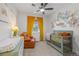 This cozy Bedroom features a crib, comfortable leather chair, a whimsical floral wall decal, and colorful artwork at 8132 Mt Harvard Rd, Littleton, CO 80125