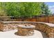A stone fire pit with built-in seating is set in a concrete patio surrounded by trees at 2948 Open Sky Way, Castle Rock, CO 80109