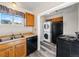 Efficient kitchen with stacked washer and dryer, black appliances, neutral countertops and wood cabinets at 1941 S Dexter St, Denver, CO 80222