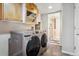 Updated laundry room features a modern washer and dryer, storage cabinets, and tile floors at 1563 Baguette Dr, Castle Rock, CO 80108