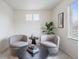 Living room area features two chairs, accent table, modern decor, large windows, and carpeted floors at 4408 Riviera Ct, Aurora, CO 80019