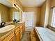 Bathroom features a double vanity with oak cabinets and a soaking tub with tile surround at 6188 Viewpoint Ave, Firestone, CO 80504