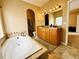Bright bathroom featuring a soaking tub, double vanity, and travertine tile flooring at 6188 Viewpoint Ave, Firestone, CO 80504