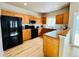 Well-lit kitchen featuring wood cabinets, black appliances, and light wood floors at 6188 Viewpoint Ave, Firestone, CO 80504