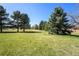A green and lush public space with a grassy field and various trees on a sunny day at 10601 W 78Th Ave, Arvada, CO 80005