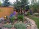Backyard featuring stone walkway, perennial flowers, and mature trees at 28665 Tepees Way, Evergreen, CO 80439