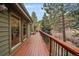 Long wooden deck with metal railing overlooking a wooded area offers a peaceful outdoor living space at 3065 Piney Ridge Rd, Evergreen, CO 80439
