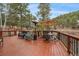 Entertain on this outdoor deck with patio seating, furniture and umbrella overlooking the treed landscape at 3065 Piney Ridge Rd, Evergreen, CO 80439