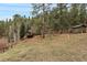 Backyard view of deck area, outbuilding, trees, and rolling hill. This property has outdoor space to enjoy at 3065 Piney Ridge Rd, Evergreen, CO 80439