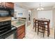 Bright kitchen featuring tile floors, dark cabinets, granite countertops, and black appliances, open to the dining area at 430 Zang St # 4-103, Lakewood, CO 80228