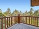 A balcony with wood railings offers stunning views of the surrounding trees and greenery at 7076 Boreas Rd, Larkspur, CO 80118