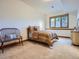 A secondary bedroom with a patterned bedspread, a vintage chair, and soft natural light at 7076 Boreas Rd, Larkspur, CO 80118