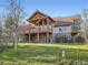 Large home featuring an expansive back deck, stone accents, and beautiful landscaping at 7076 Boreas Rd, Larkspur, CO 80118