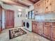 Charming laundry room featuring pine cabinets, stone floors, and modern washer and dryer at 7076 Boreas Rd, Larkspur, CO 80118