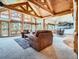 Bright living room with exposed wood beams, a wall of windows, and plush seating area provides comfort at 7076 Boreas Rd, Larkspur, CO 80118