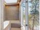 Spa-like bathroom featuring a unique tile design, a sunken tub and a window with beautiful outdoor views at 4966 Delaware Dr, Larkspur, CO 80118