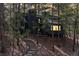 Modern mountain home at dusk nestled among mature trees with light glowing inside at 4966 Delaware Dr, Larkspur, CO 80118