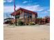 Inviting home with a large front porch, American flag and well-maintained landscaping against a bright blue sky at 16659 County Road 4, Brighton, CO 80603