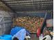 Storage shed interior piled high with cut wood and covered with a blue tarp at 16659 County Road 4, Brighton, CO 80603