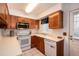 Traditional kitchen with white appliances, tile flooring, wood cabinets, and a bright window at 14272 E Hawaii Cir # B, Aurora, CO 80012