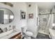 Bathroom showcasing a round mirror, wood vanity, sink, toilet, framed art, and shower with marble tile at 450 Yukon St, Lakewood, CO 80226