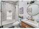 Bathroom with tub and shower, marble tile, wood vanity, sink, toilet, and decor at 450 Yukon St, Lakewood, CO 80226