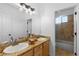 Bright bathroom featuring double sinks, granite countertops, wood cabinets, and a shower at 5653 Yank St, Arvada, CO 80002