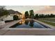 Inviting pool surrounded by lush landscaping, with reflection of home and sky on water's surface at 5653 Yank St, Arvada, CO 80002