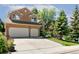 Tan two-story home with a two-car garage and well-manicured lawn and mature trees in a suburban neighborhood at 531 Saber Creek Dr, Monument, CO 80132