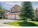 Two-story home with a two-car garage, green lawn and landscaping, with a focus on trees at 531 Saber Creek Dr, Monument, CO 80132